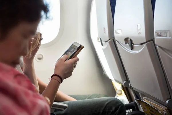 Держите в руках мобильный телефон, сидя внутри самолета — стоковое фото
