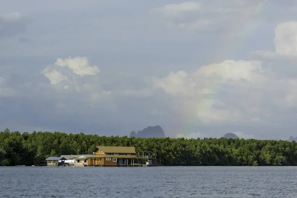 floating house in front of banyan tree after raining with rainbo