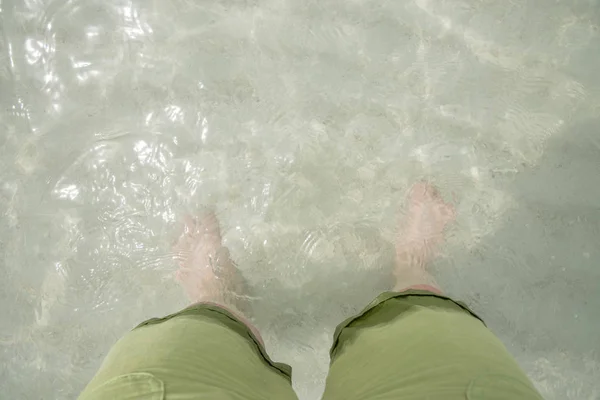 Leg with shorts in sea and sand,reflexion in water,summer concep