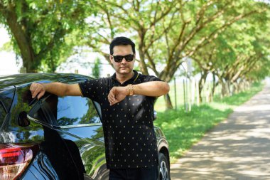 Müslüman rahat iş adamı yaslanmış againt arabanın kapısını ve w bakmak