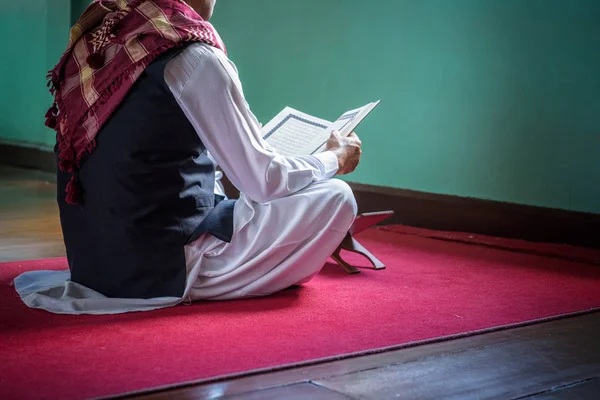 Islam hombre musulmán en vestido musulmán leer el libro sagrado del Corán en s —  Fotos de Stock