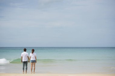 Genç Asyalı çift beach bakmak için el birlikte stand tutun