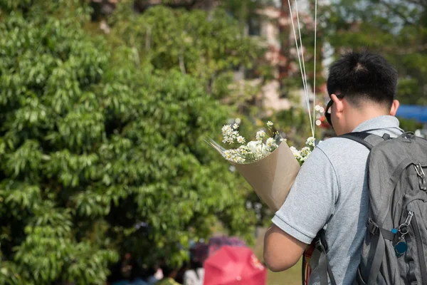 Азиатский мужчина носить очки руку бранч цветок стоять сзади — стоковое фото