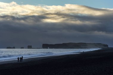 Gezgin Reynisfjara siyah kum plaj ve dağ ile