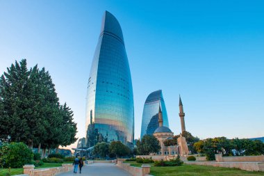 Arka planda Alev Kuleleri olan çift yürüyor. Hazar Denizi kıyısında yer alan Azerbaycan 'ın başkenti Bakü' nün panoramik manzarası.