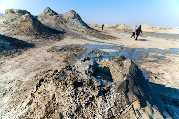 Schlammvulkan mit Touristen im Hintergrund im Gobustan Nationalpark, azerbaijan.brodelnder Krater eines Schlammvulkans. — Stockfoto