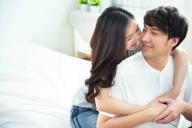 Asyalı genç bir çiftin portresi olan kadın yüzü üzerine seçici bir odak. Yatakta sırtüstü uzanmış, sırtüstü uzanmış, romantik Asyalı, aşık insanlar yatakta otururken sarılıyor. Kopya uzaylı sevgililer günü konsepti..