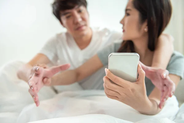 Secretly listening to conversation over phone or peeping social posts, messages.Asian young man and woman fight over on smart mobile phone with argument relationship concept