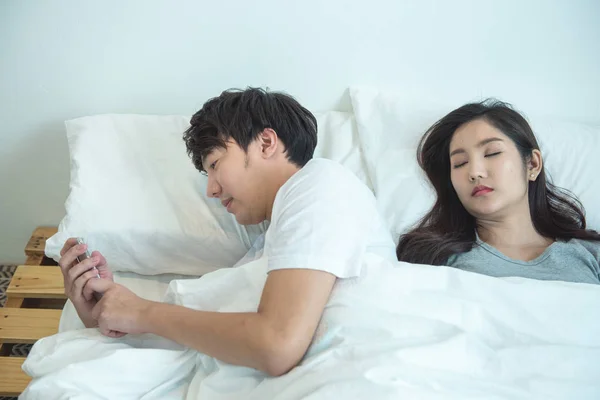 Asiatique jeune homme utiliser téléphone mobile intelligent bavarder secret sur le lit tandis que sa petite amie sommeil. petit ami tricherie secrètement utiliser téléphone portable, mode de vie relation problème social . — Photo