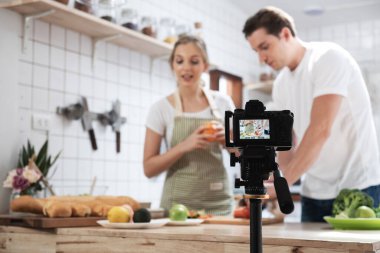 Mutfakta yemek yapan mutlu beyaz çiftin video blogunu kaydeden profesyonel dijital aynasız kamera, fotoğrafçı ya da video ve canlı yayın konsepti, Vlogger ve blog yazarı.