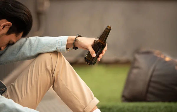 中毒空腹の酔った男は、手元にビールのボトルを保持し、不活性な睡眠.財政的な問題に苦しんで失業した若いアジアの男絶望感使用アルコールストップ痛み. — ストック写真
