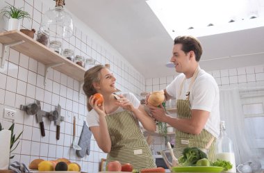 Kafkasyalı mutlu bir çift, modern mutfakta aşkla yemek pişiriyor. Evli erkek ve kadın taze sebze salatası pişiriyor. Sağlıklı yaşam tarzı konsepti..