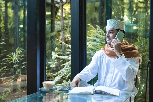 Arab muslim businessman use smartphone communication and write on book in coffee shop ,freelance no working space lifestyle. — Stockfoto