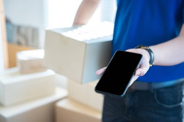 Üniformalı genç teslimatçı elinde akıllı telefonu boş ekranla gösteriyor. Ulaşım teknolojisi kavramı..