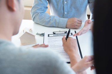 Mutlu Genç Asyalı Çift ve emlak ajan. Eşi ile birlikte masada otururken bazı belgelerin imzalanması neşeli genç adam. Yeni ev gayrimenkul satın almak. İyi durumda sözleşme imzalama.