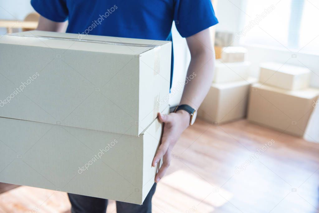 Asian young delivery man holding and carrying two cardbox standing in workplace.