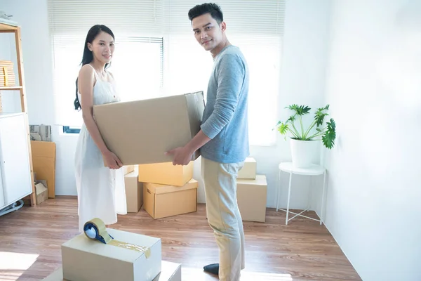 asian couple receive shipment from delivery man, order box shipping from online store website to deliver at home. Courier domestic logistic service business to between sender and receiver