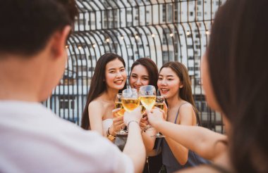 Bir grup güzel, mutlu Asyalı kadın ellerinde şarap kadehiyle arkadaşlarıyla sohbet ederken açık çatı klübünde dans partisini kutluyorlar. Genç arkadaşlığın eğlence yaşam tarzı konsepti..