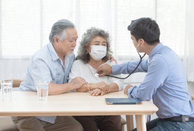 Yaşlı yaşlı bir kadınla yaşlı bir adamın dosyalarının incelenmesinin sonucu olarak konuşan beyaz bir doktor. Yaşlı bir adamla birlikte yaşlı bir Asyalı kadın. Ona iyi bakın. Sağlık ve tıbbi konsept..