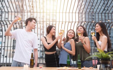 Asyalı çoklu cinsiyetli bir grup ellerinde şarap kadehiyle arkadaşlarıyla sohbet ederken açık hava gece klübünde dans partisini kutluyorlar. Genç arkadaşlıktan keyif alan eğlenceli yaşam tarzı..