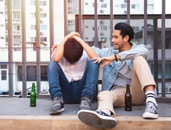 Two friends drink beer in a pub on the street. People, men, leisure, friendship and holiday concept - happy male friends drinking beer in bar or pub outside.