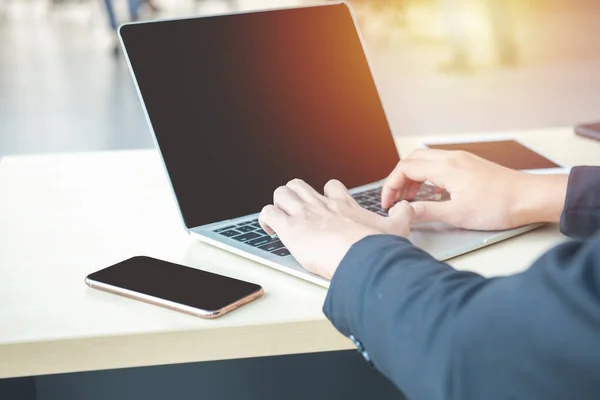 Asyalı iş adamı elleri dizüstü bilgisayarın klavyesinde iş grafiği çizelgesi veri formları, cep telefonu ve modern merkez ofisin masasında bir fincan kahve yazıyor. Dijital pazarlama kavramı.