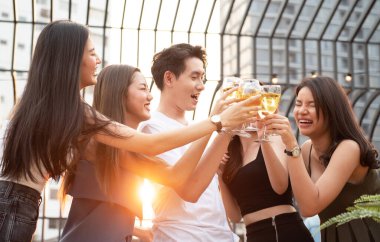 Asyalı çoklu cinsiyetli bir grup ellerinde şarap kadehiyle arkadaşlarıyla sohbet ederken açık hava gece klübünde dans partisini kutluyorlar. Genç arkadaşlıktan keyif alan eğlenceli yaşam tarzı..