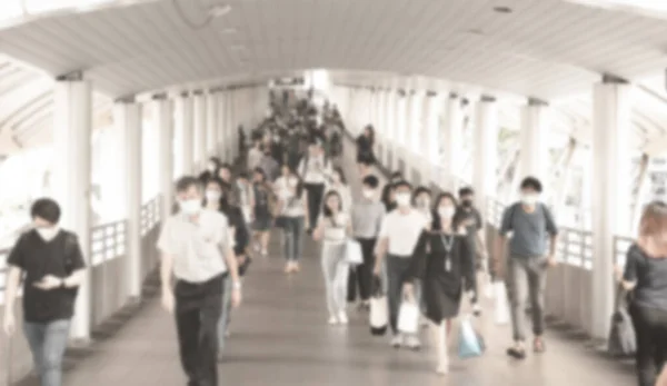 Defocused crowd wearing medical masks for virus protection and walking in walkway, blurred background, coronavirus, china covid-19 virus epidemic, pandemic, outbreak and air pollution concept