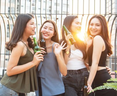 Bir grup güzel, mutlu Asyalı kadın ellerinde bira şişesiyle arkadaşlarıyla dışarıda çatıda dans ederken reklam için fotokopi çekilen bir gece kulübünde arkadaşlarıyla sohbet ediyorlar..