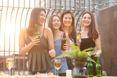 Bir grup güzel, mutlu Asyalı kadın ellerinde bira şişesiyle arkadaşlarıyla dışarıda çatıda dans ederken reklam için fotokopi çekilen bir gece kulübünde arkadaşlarıyla sohbet ediyorlar..