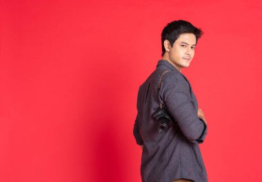 Mutlu Asyalı genç hippi fotoğrafçı, günlük moda. Eski moda kamera özgürlüğü seyahat konseptini kullanıyor. Kırmızı arka plan stüdyo çekimlerinde izole edilmiş..