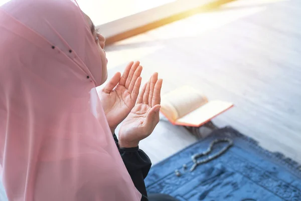 side view of asian beautiful young muslim student woman prayer in hijab praying on carpet mat indoors