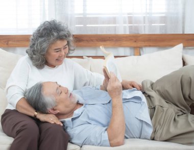 Kıdemli Asyalı adam kanepede uzanıp büyükannemle oturma odasında kitap okudu..