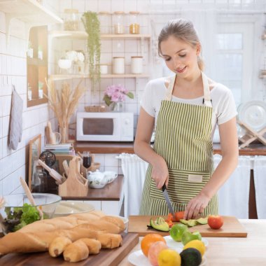 Genç beyaz kadın mutfakta yemek pişiriyor. Sağlıklı yemek ve diyet konsepti. Sağlıklı bir yaşam tarzı. Evde yemek yapan genç bir ev hanımı.. 