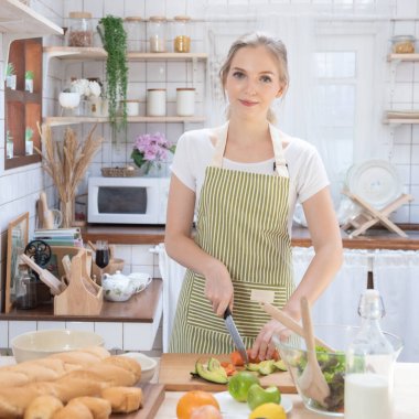 Genç beyaz kadın mutfakta yemek pişiriyor. Sağlıklı yemek ve diyet konsepti. Sağlıklı bir yaşam tarzı. Evde yemek yapan genç bir ev hanımı.. 
