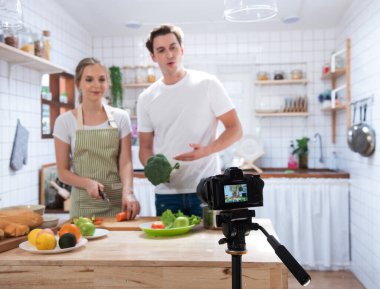 Mutfakta yemek yapan mutlu beyaz çiftin video blogunu kaydeden profesyonel dijital aynasız kamera, fotoğrafçı ya da video ve canlı yayın konsepti, Vlogger ve blog yazarı.