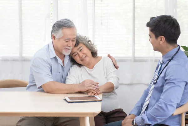 Young caucasian doctor man talking result of examination on tablet to senior elderly old retirement asian woman with old man take care her beside.healthcare and medical concept.