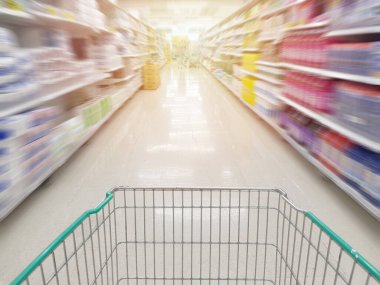 Marketteki ürün raflarının hareket bulanıklığıyla dolu olan Trolley boş alışveriş arabası, Coronavirus covid-19 kriz tecridi müşterisi ürünleri bitmeden önce stok yapıyor..