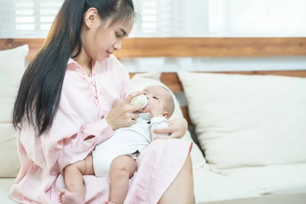 이시아 어미는 젖병으로 아기에게 먹인다 아시아 엄마의 컨셉트 플래그를 사용하여 — 스톡 사진