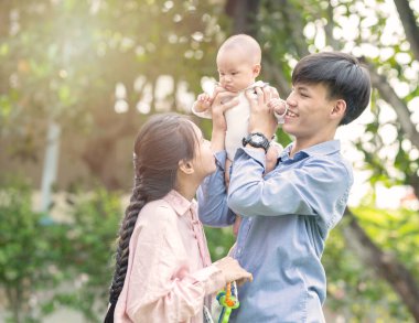 Mutlu aile kavramı. Mutlu genç Asyalı çift ebeveyn küçük oğluyla eğleniyor baba kucağında kucağında kucağında kucağında kucağında kollarıyla anne sevgisiyle ayakta duruyor..