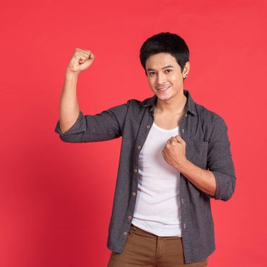 Heyecanlı şanslı Asyalı genç öğrenci kolaj üniversitesi kazananı kırmızı stüdyonun arka planında izole edilmiş kameraya bakarak sevinçten çığlık atıyor.