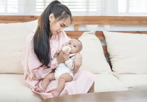孩子和父母的概念 快乐美丽的年轻的亚洲母亲微笑着抱着新生儿 在家里的沙发上喂奶 带有广告复制空间的横幅 — 图库照片