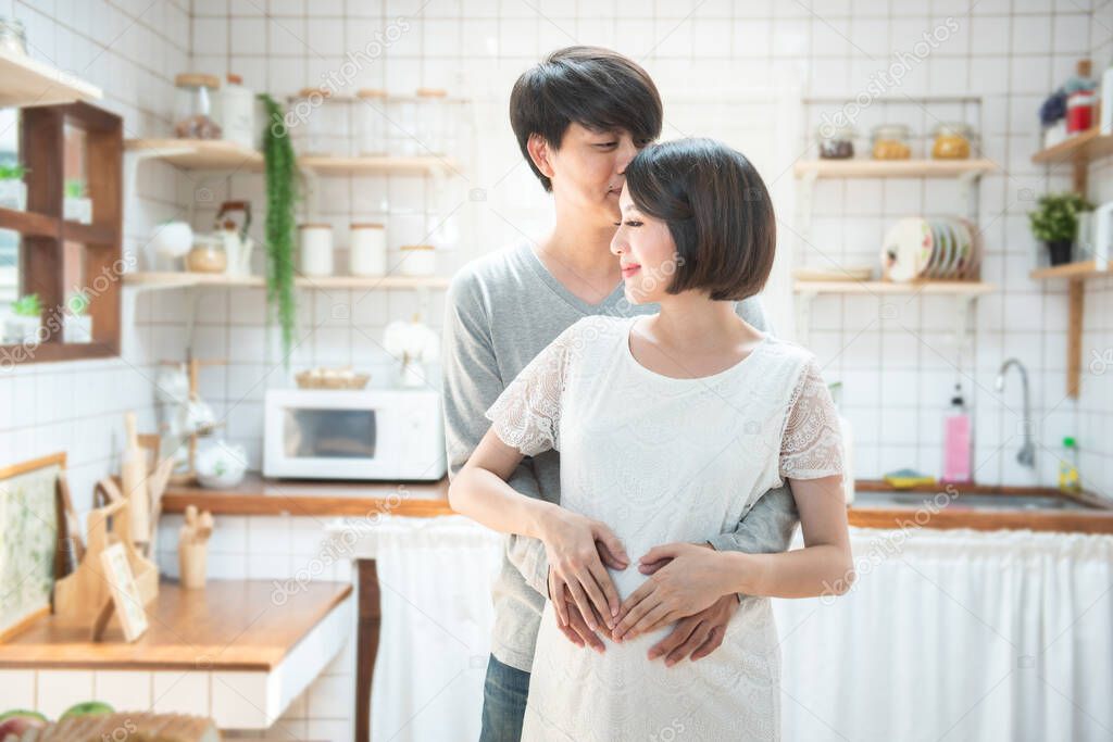 pregnancy concept - couple making heart shape with their hands on pregnant belly