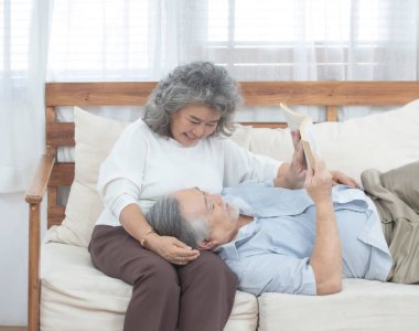 Kıdemli Asyalı adam kanepede uzanıp büyükannemle oturma odasında kitap okudu..