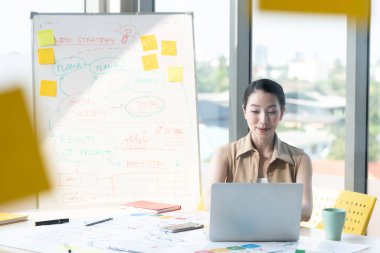 Asyalı güzel girişimci internette bilgisayar ve çizelge tahtası ile ofis veya çalışma masasında çalışıyor, evde çalışıyor ve sosyal uzaklık koronavirüsü veya covid-19 sağlık konseptini koruyor