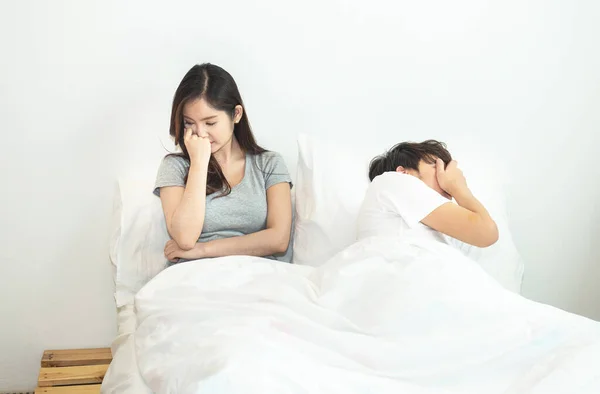 young asian couple in bed having problems and crisis man and woman hands cover head with confused unhappy separate from each other.Divorce and separation.