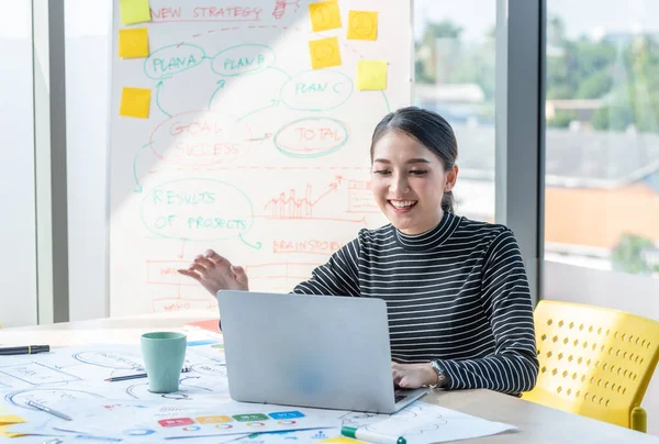 Asyalı güzel girişimci internette bilgisayar ve çizelge tahtası ile ofis veya çalışma masasında çalışıyor, evde çalışıyor ve sosyal uzaklık koronavirüsü veya covid-19 sağlık konseptini koruyor