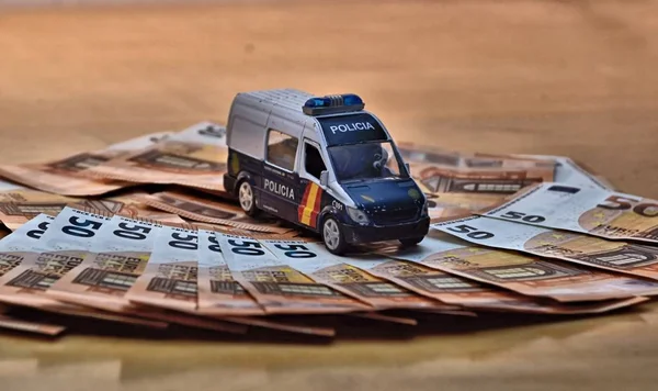 Realistic, Spanish toy police car standing on a pile of euro banknotes.