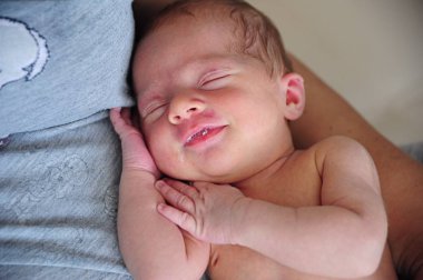 Little beautiful newborn is sleeping sweetly on happy mummy`s hands. He is smiles sweetly in a dream clipart