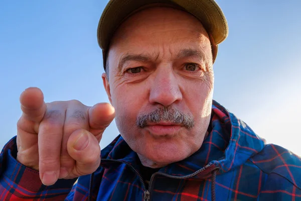 Un hombre con bigote y gorra muestra sus cuernos con la mano . — Foto de Stock